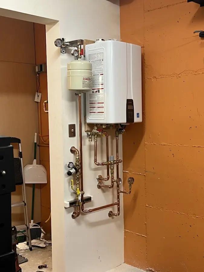 Plumbing technician inspecting water heater connections in St. Charles